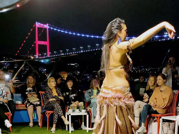Belly dancer at a Bosphorus dinner cruise with the lit bridge behind