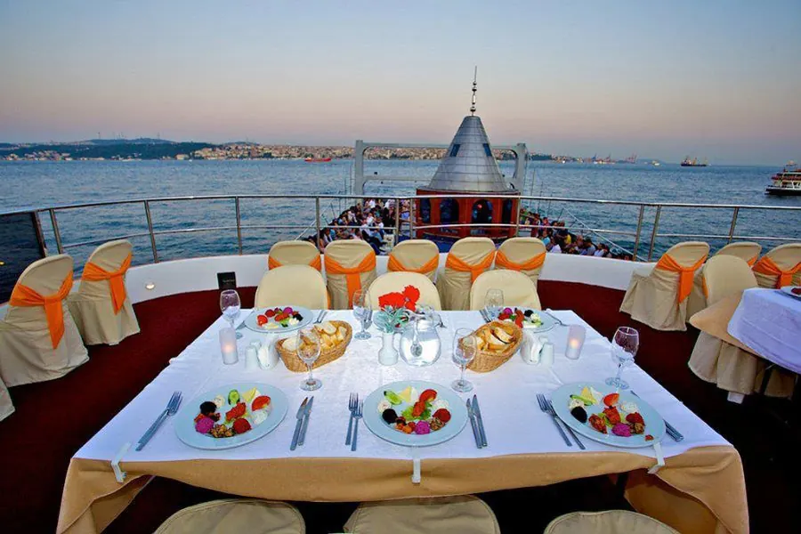 Mesa VIP en la cubierta superior del barco del crucero con cena al anochecer