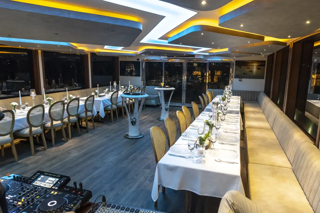 Event yacht saloon with a DJ booth and dinner tables