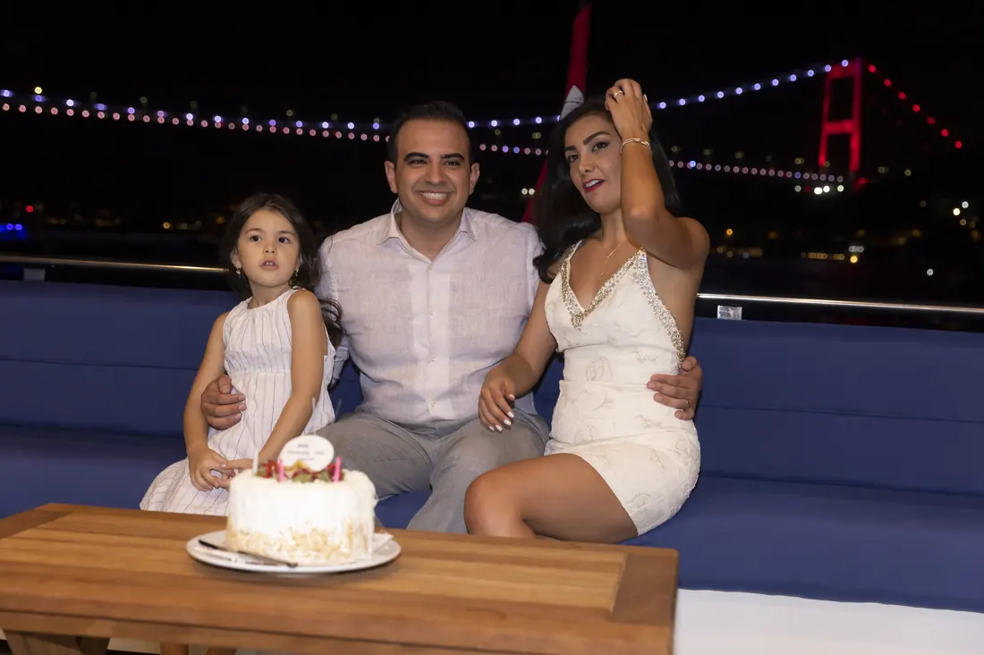 Family with a cake on a yacht near the Bosphorus Bridge
