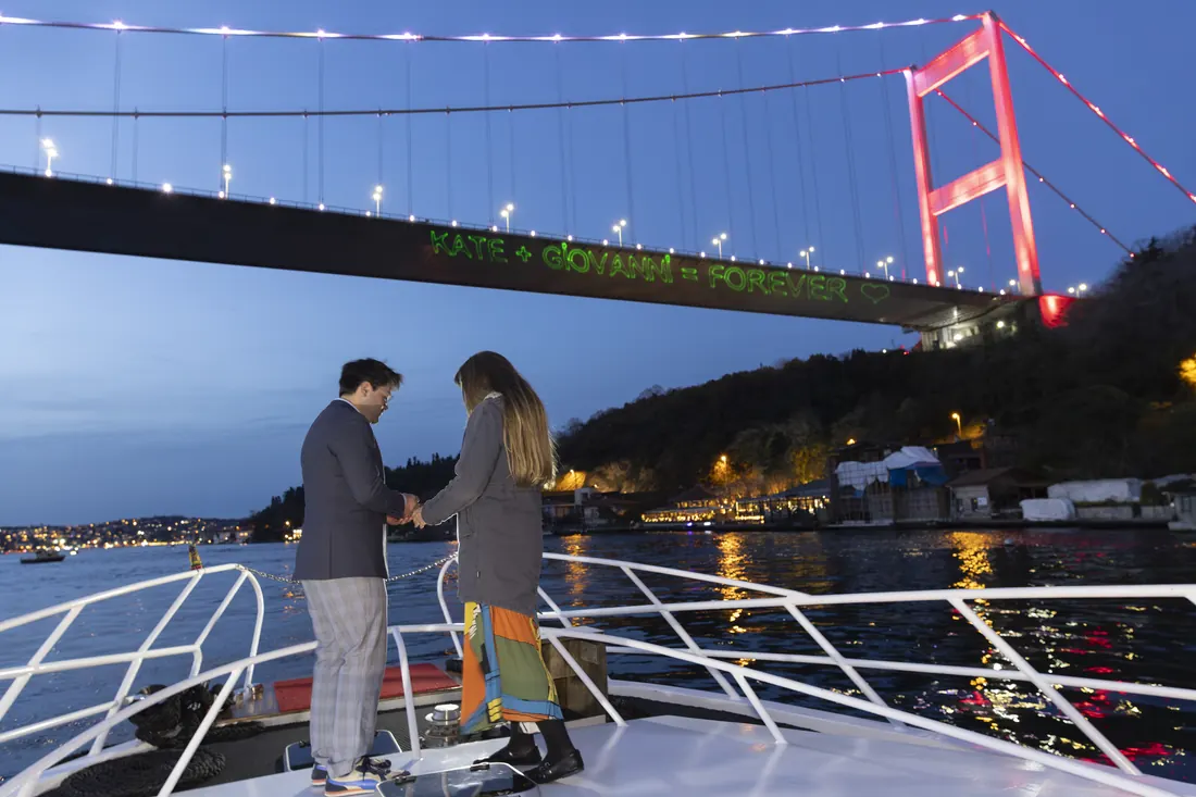Couple on the bow with a laser message on the Bosphorus Bridge