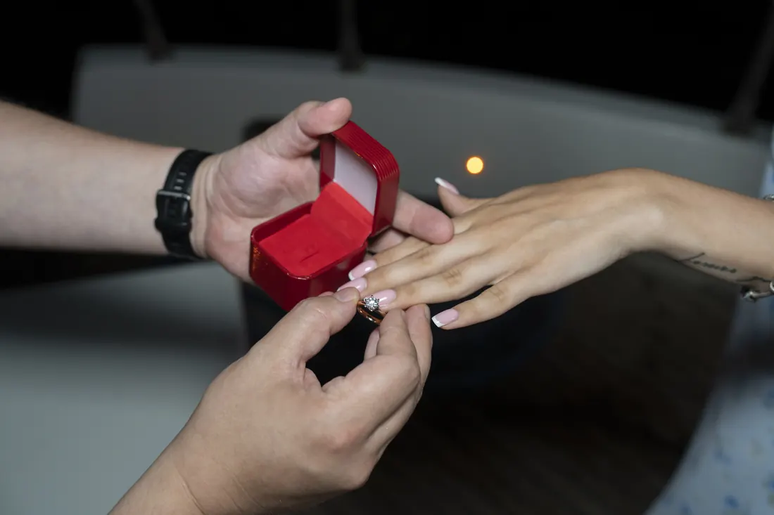 Engagement ring being placed on her finger on a yacht