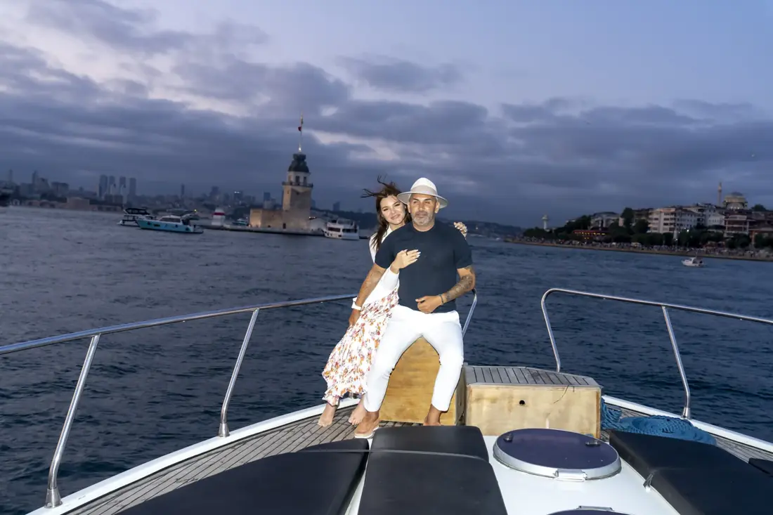 Couple on the bow of a private yacht in front of the Maiden's Tower at dusk