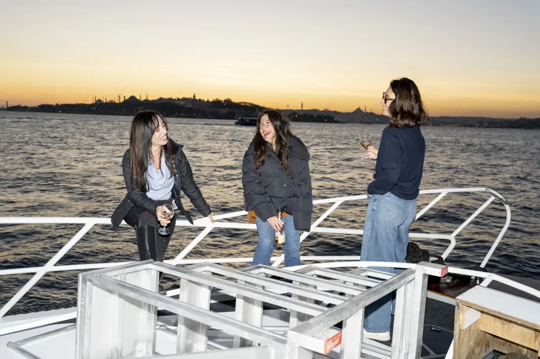 Friends laughing on the deck of a private yacht at sunset on the Bosphorus