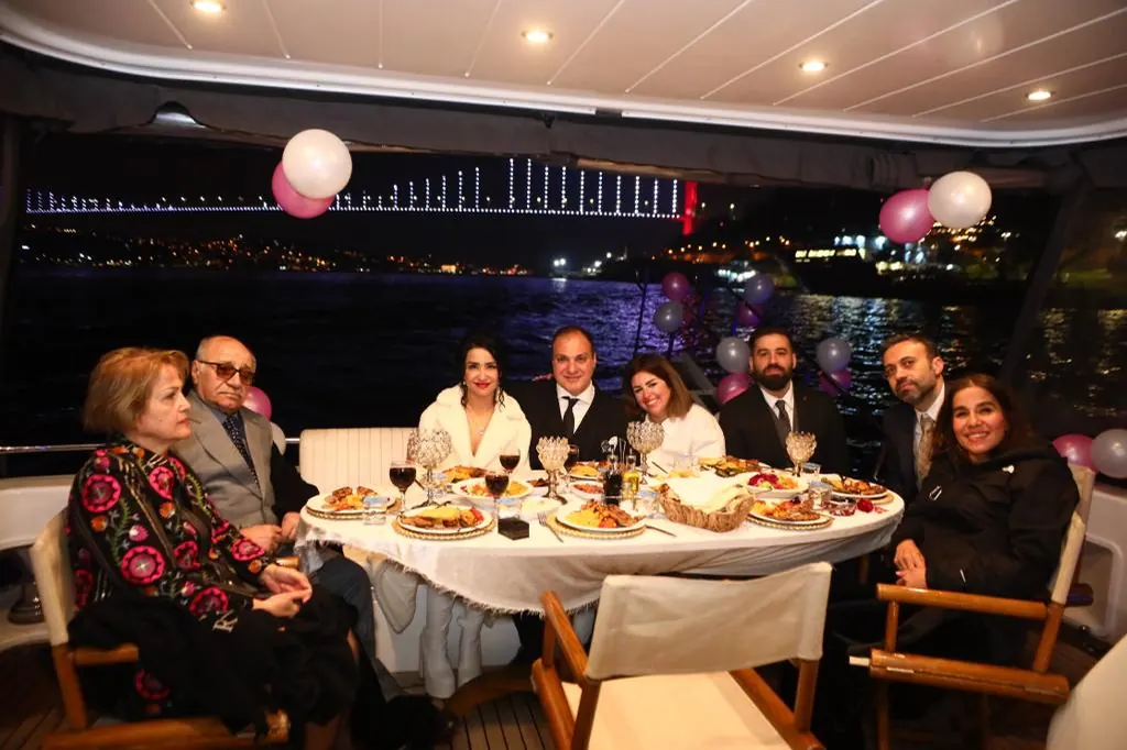 Family celebrating at dinner on the deck of a private yacht at night