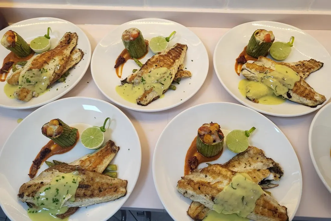 Plates of grilled sea bass ready to serve on a yacht