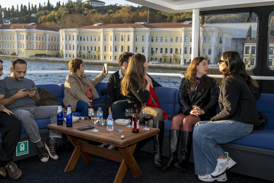 Guests relaxing in the lounge of a yacht with a waterfront palace behind