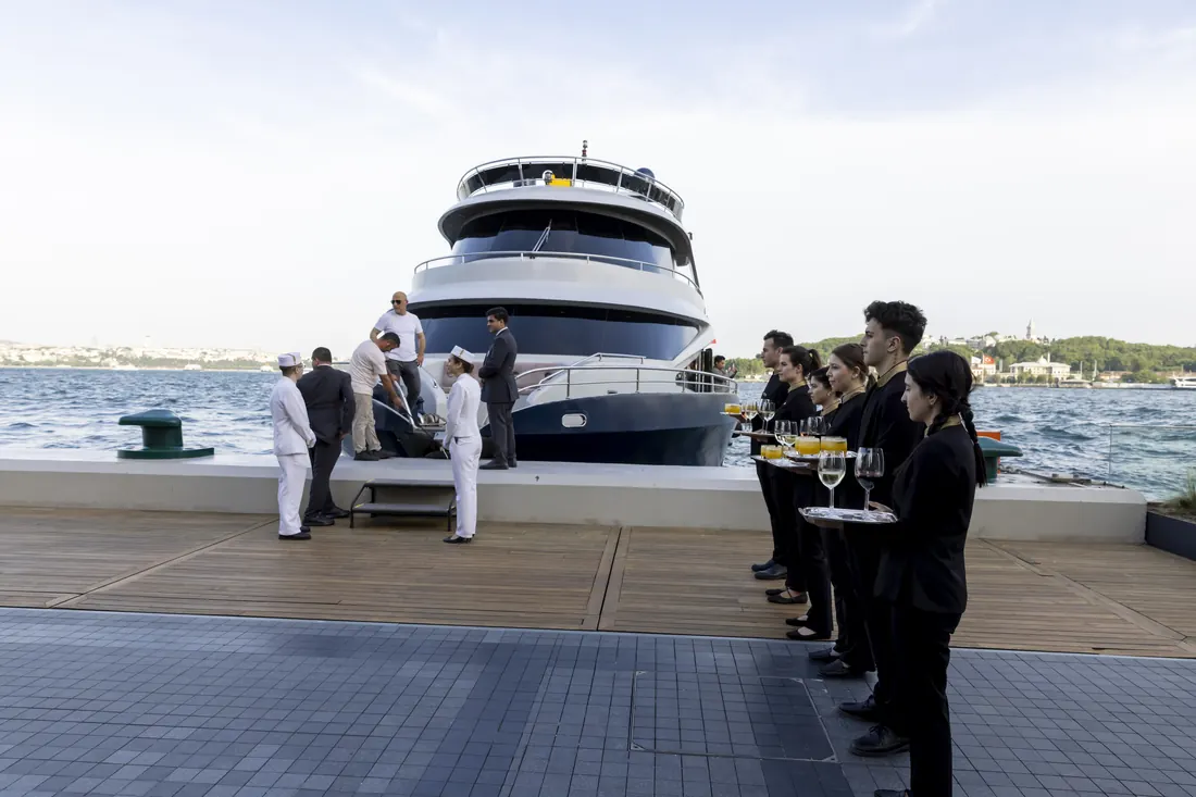 Crew welcoming guests beside an event yacht at the pier
