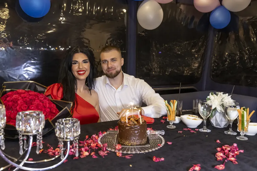 Table with red roses, candles and a cake decorated for a celebration on a yacht
