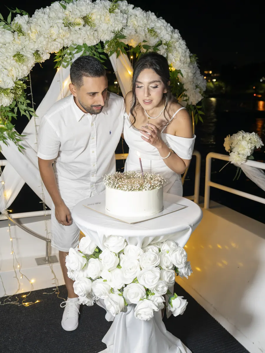 Couple cutting the wedding cake under a flower arch