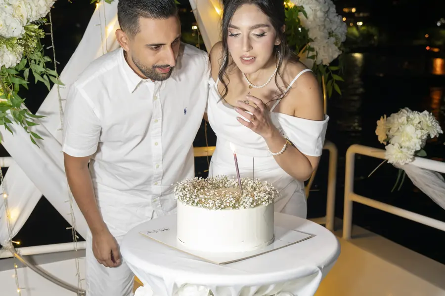 Newlyweds cutting their wedding cake under a flower arch